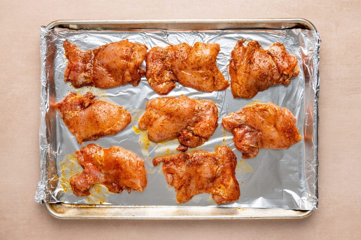 seasoned chicken on foil-lined baking sheet
