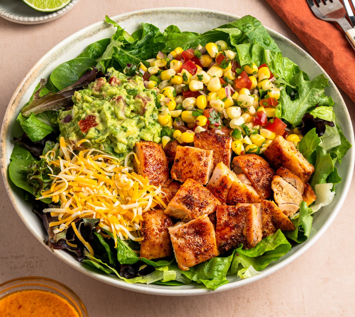Copycat chipotle chicken in bowl with greens, corn salsa, guacamole and cheese.