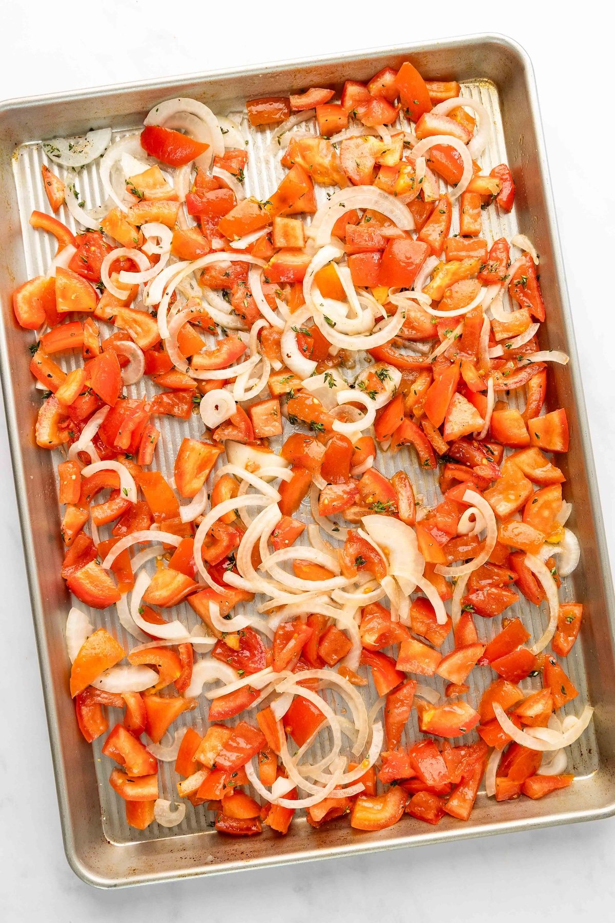 baking sheet with tomatoes, onions, olive oil, salt, pepper, sugar, and thyme