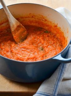 Wooden spoon in a Dutch oven of homemade tomato sauce.