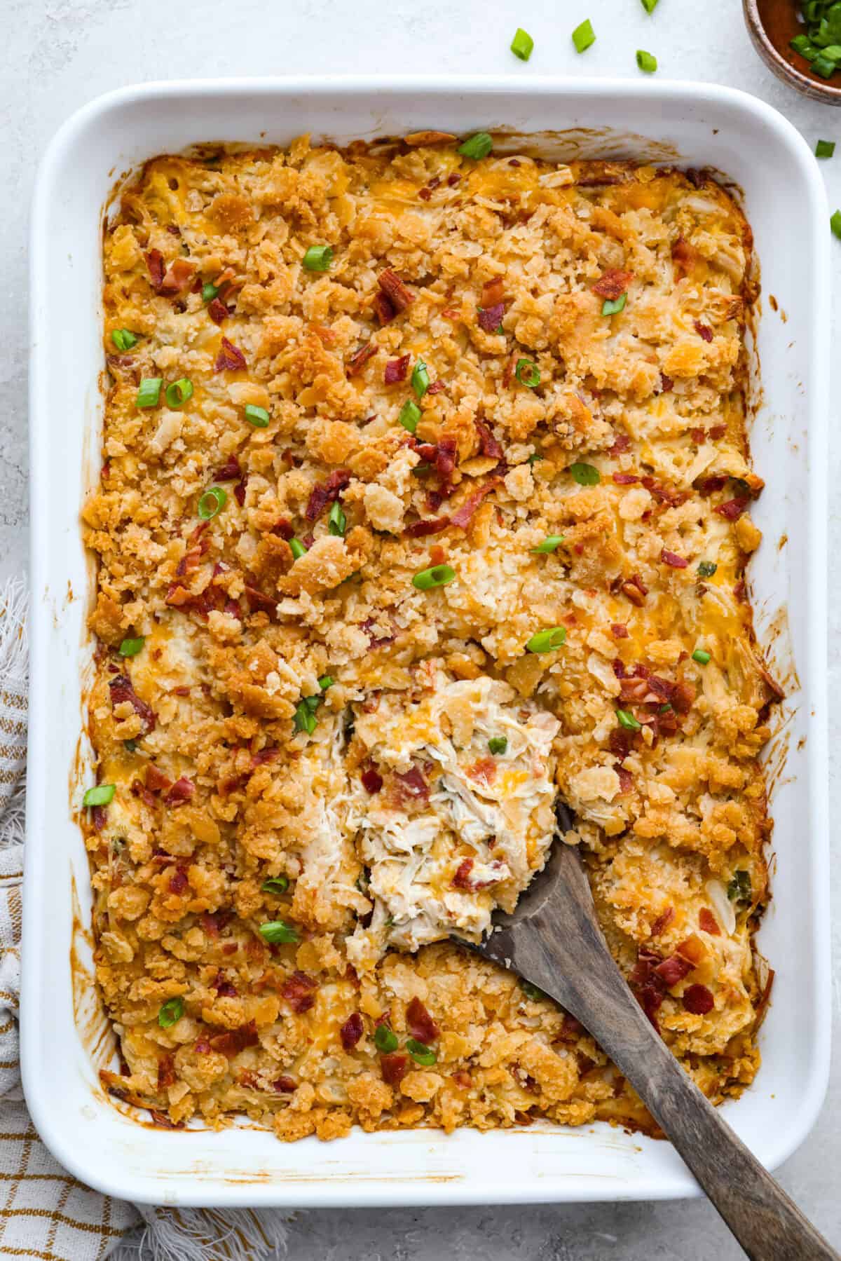 Overhead shot of a baked Neiman Marcus chicken casserole with a wooden spoon in it. 