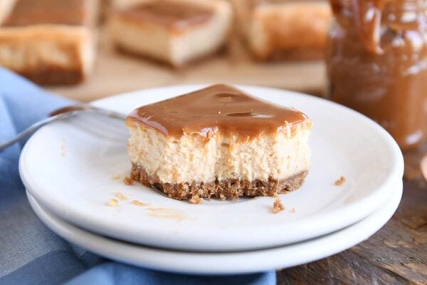 dulce de leche cheesecake square on white plate with bite taken out