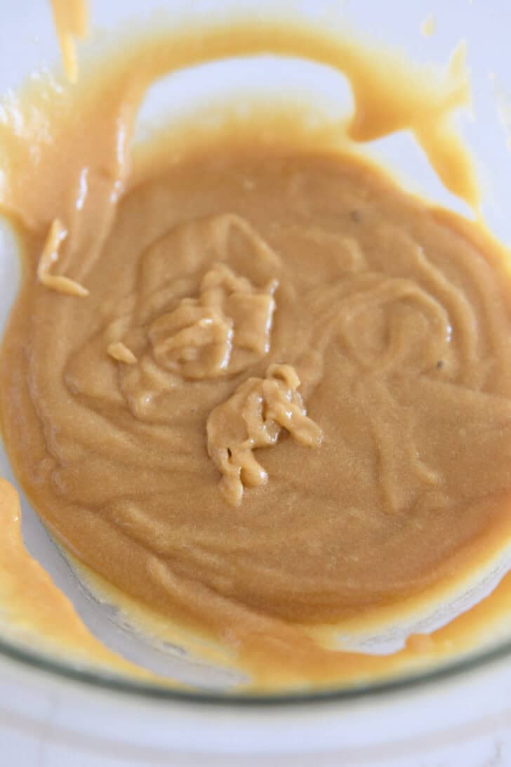 Mixed mixture of eggs, brown sugar, white sugar and olive oil in glass bowl.