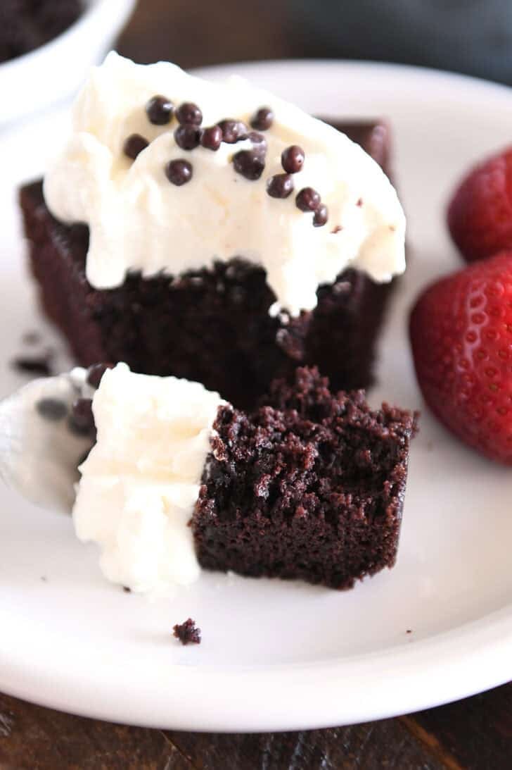 Fork with bite of chocolate olive oil cake and whipped cream.
