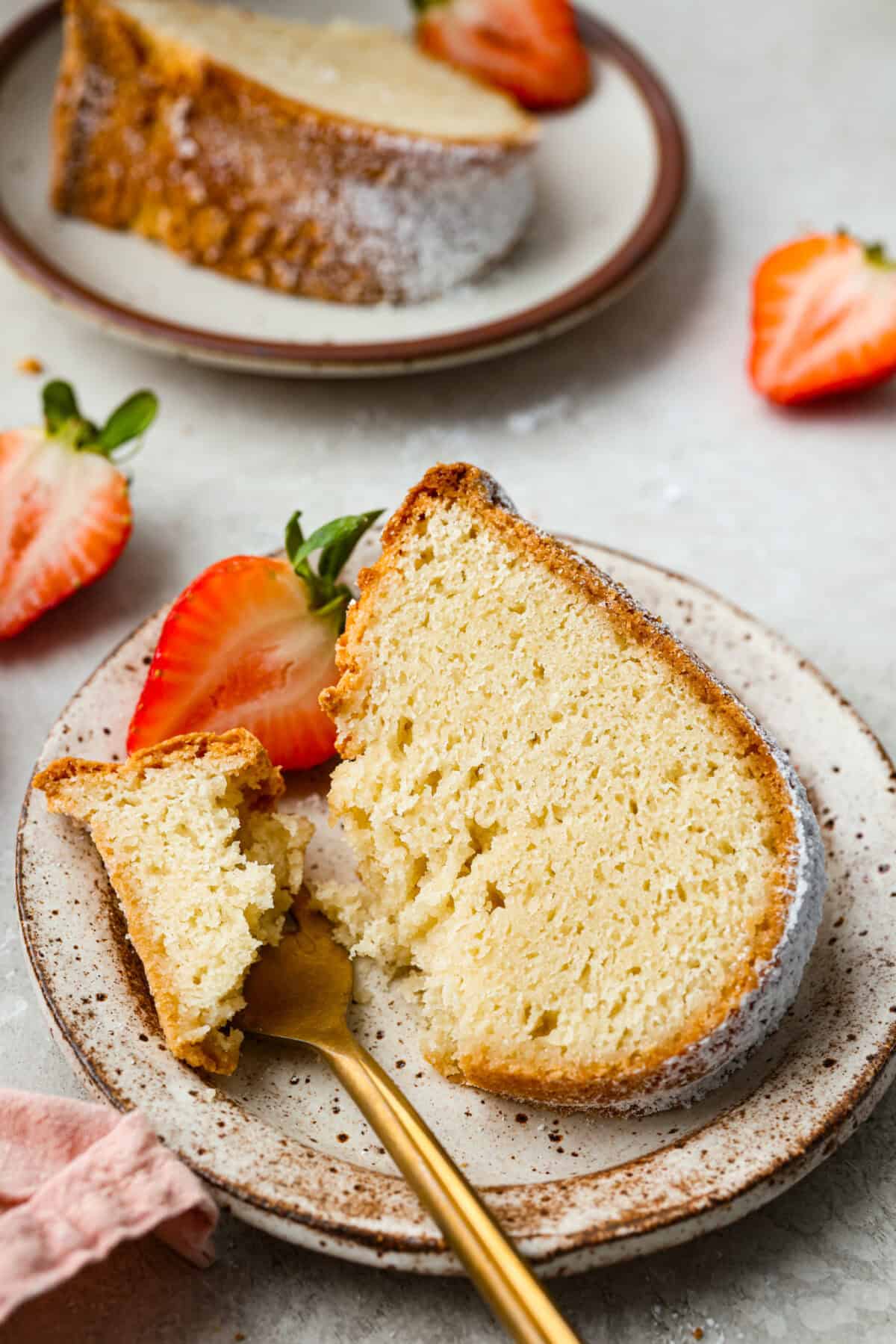 Plated slice of sour cream pound cake garnished with a strawberry. 