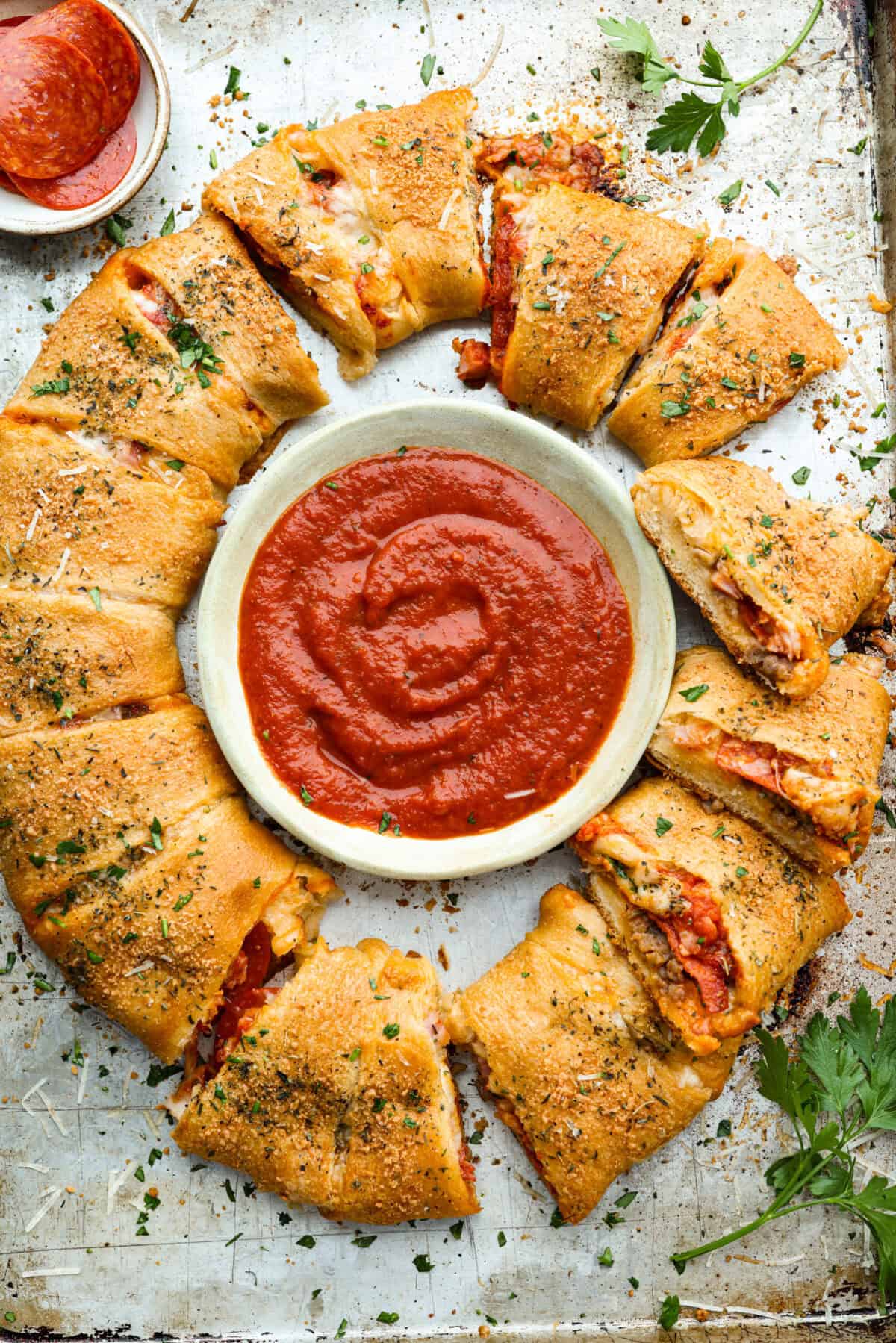 Overhead shot of the baked pizza ring with a bowl of marinara sauce in the middle. 