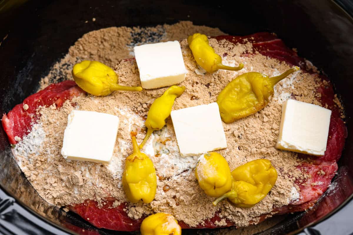 Chuck roast covered in the seasoning packets, butter, and  peppers. 