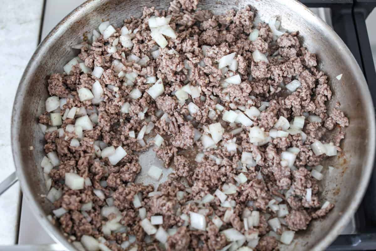 Ground beef and onions cooking in a skillet.