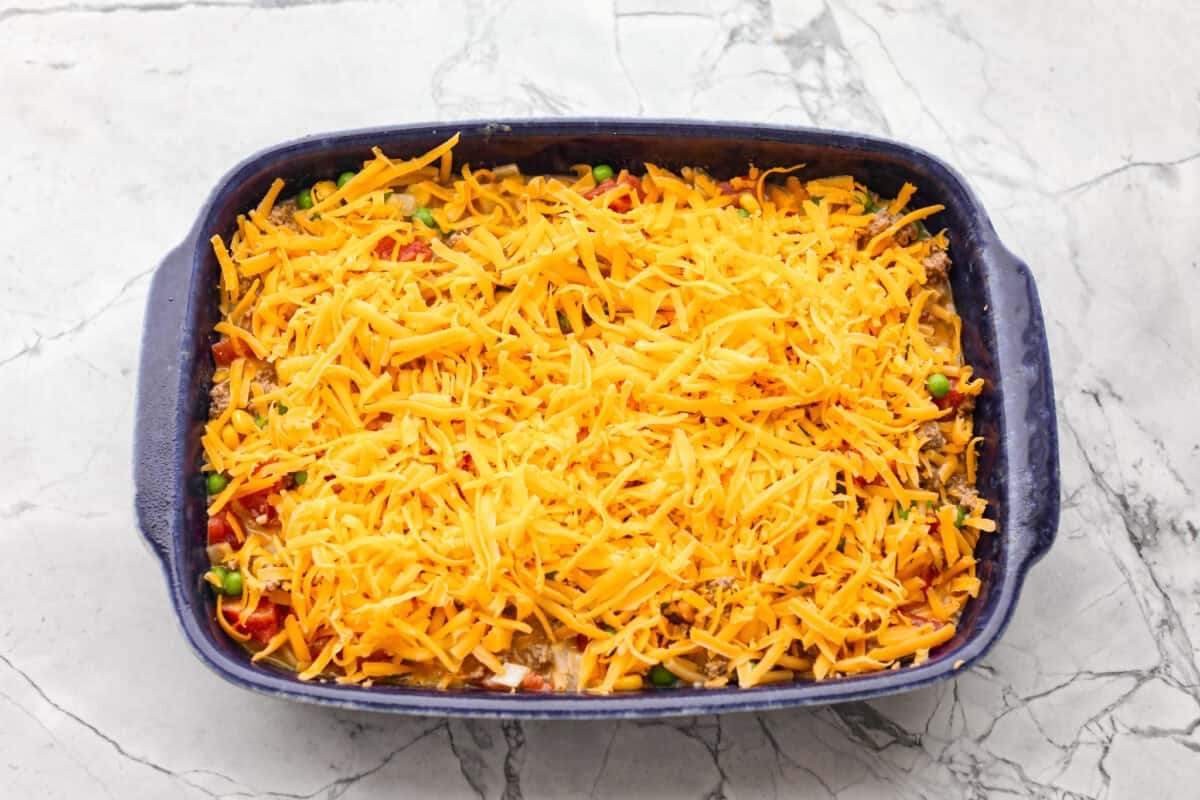 All of the ingredients added to the baking topped with cheese and ready to go in the oven.