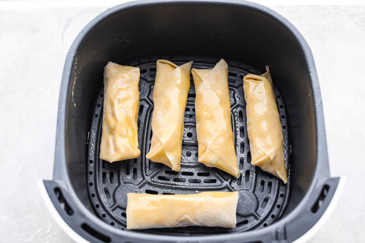 Crack Chicken Egg Rolls wrap savory chicken, crispy bacon, melty cheese, and zesty ranch in a golden, crunchy shell. Easy to make, lighter than deep-fried versions, and perfect for parties or game day! Egg rolls spaced evenly in the bottom of the air fryer basket.