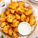 buffalo cauliflower bites in napkin lined basket with ramekin of blue cheese dressing