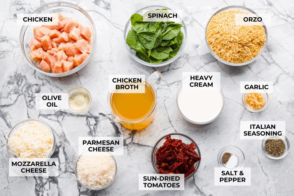 Overhead shot of labeled tuscan chicken orzo bake ingredients.