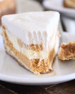 Slice of pumpkin swirl cheesecake with bite removed on white plate.