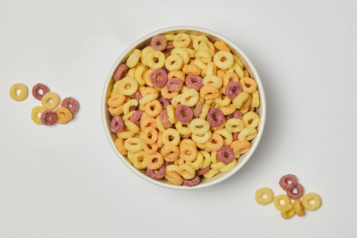 Molino Nicoli-Bowl of colorful fruity hoops cereal. Breakfast food, yellow, orange, and purple hoops.