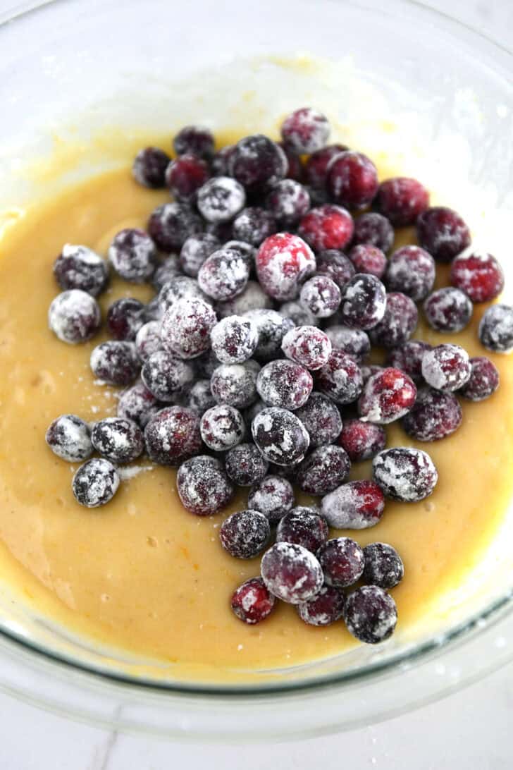 Flour dusted fresh cranberries in bowl with quick bread batter.