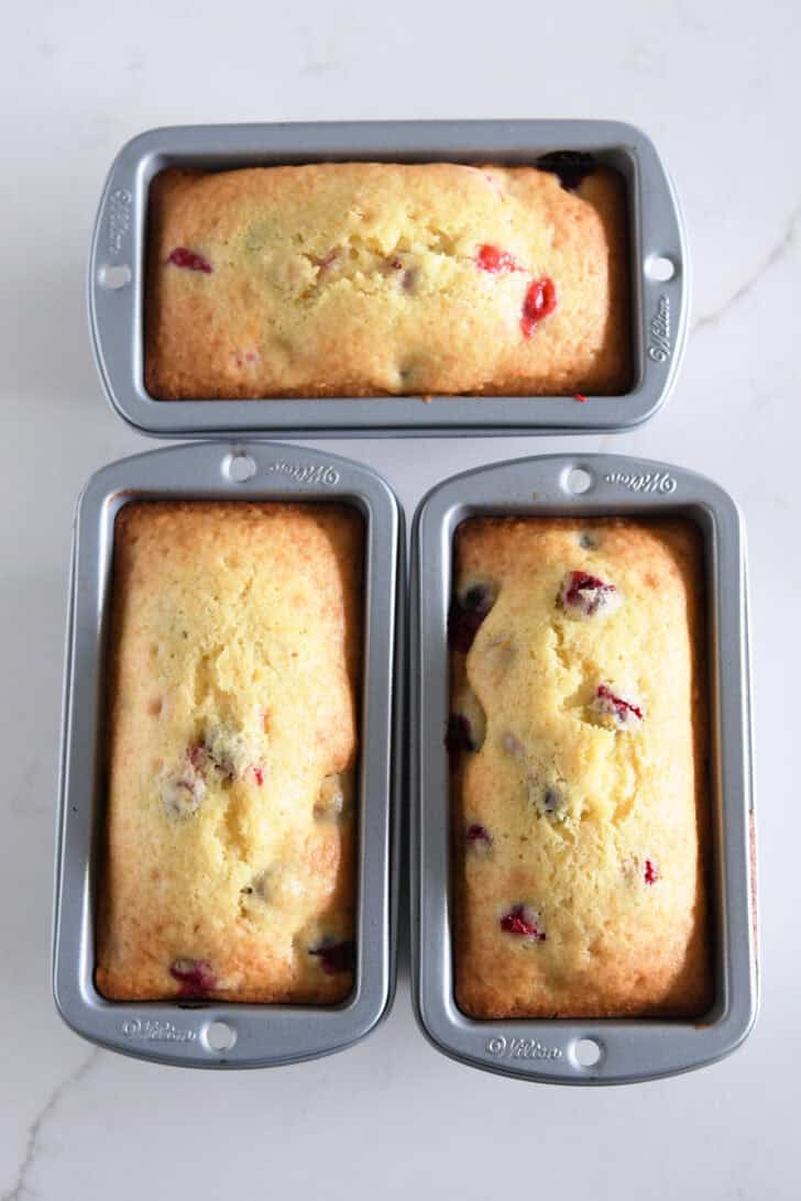Top down view of three mini loaf pans with baked cranberry orange bread.