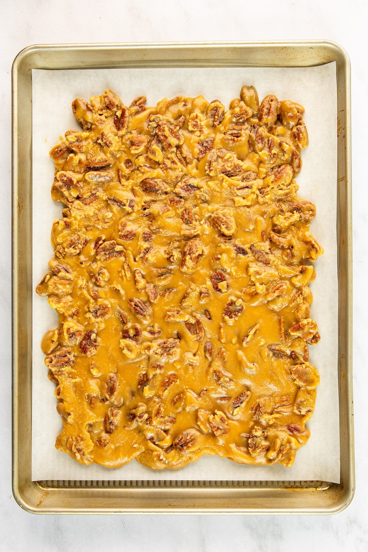 praline mixture cooling on parchment-lined baking sheet