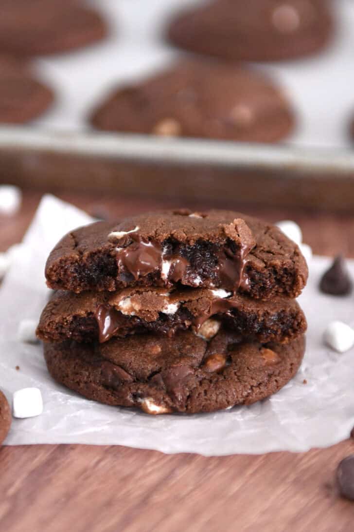 Two half chocolate cookies with gooey melted chocolate chips and mini marshmallows stacked on one full cookie.