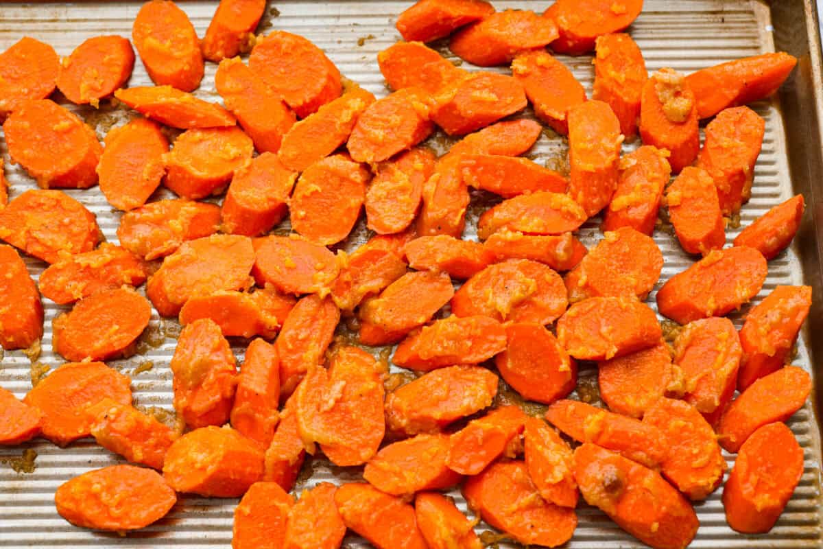 Glazed carrots spread out on a baking sheet.