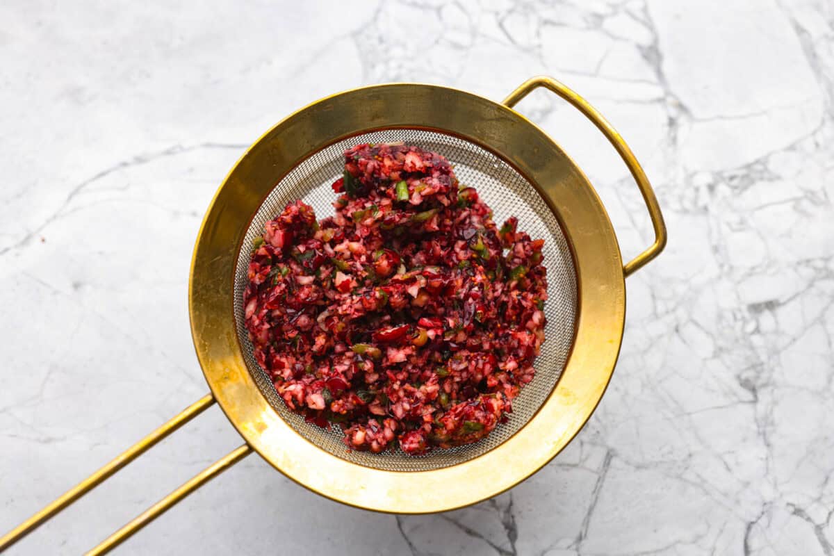 Cranberry mixture in a fine mesh strainer being drained. 