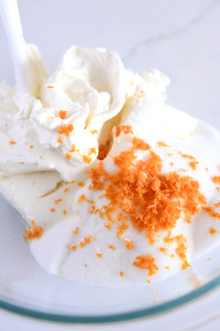 Glass bowl with cream cheese, sugar and fresh orange zest.