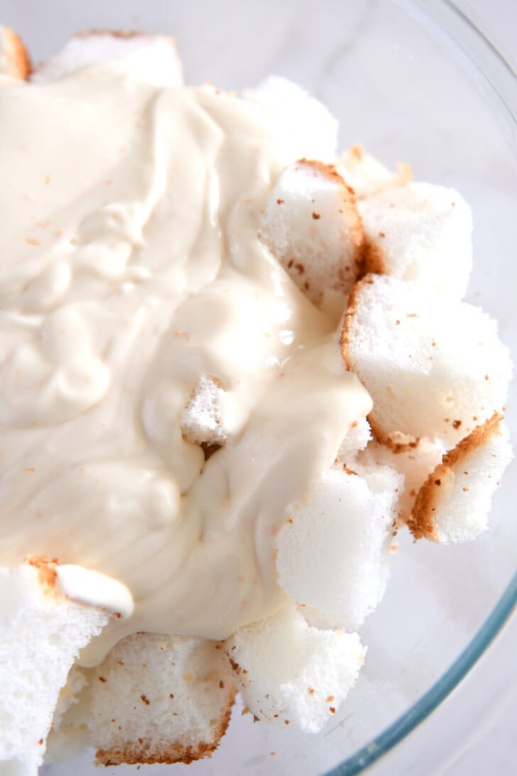 Glass bowl with angel food cake cubes and cream mixture.