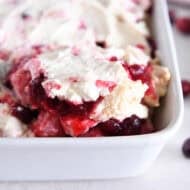 Scoop of cranberry orange angel food cake cubes in white baking dish.