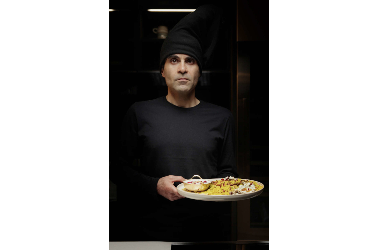 Chef Ali of Urbani Tartufi holds a plate of truffle-infused cuisine. Gourmet food presentation.