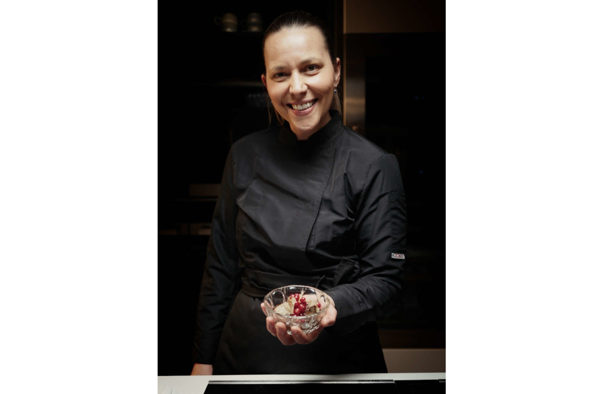 Chef Patricia of Urbani Tartufi presents a truffle dish. Culinary expert smiles, showcasing gourmet food.