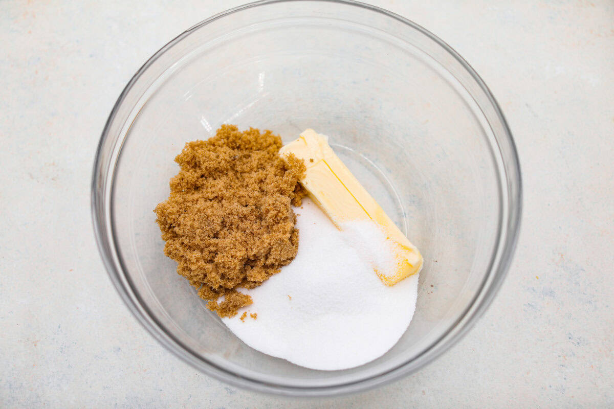 Sugar and butter added to a mixing bowl. 