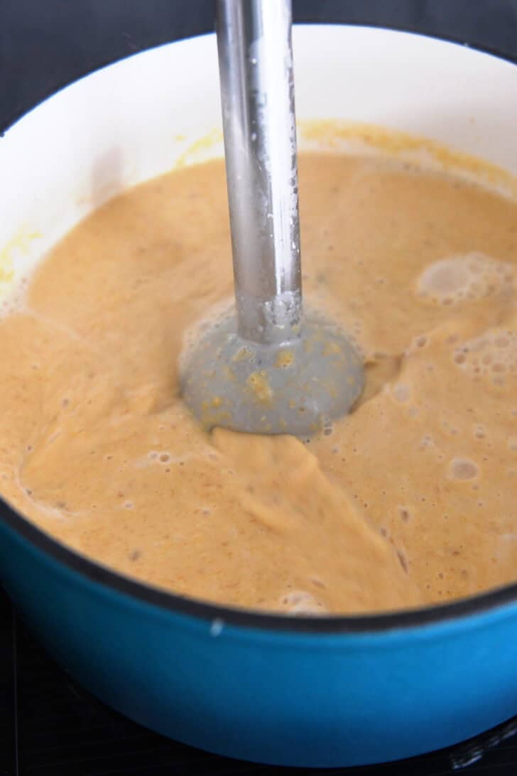 Immersion blender blending butternut squash soup in soup pot.