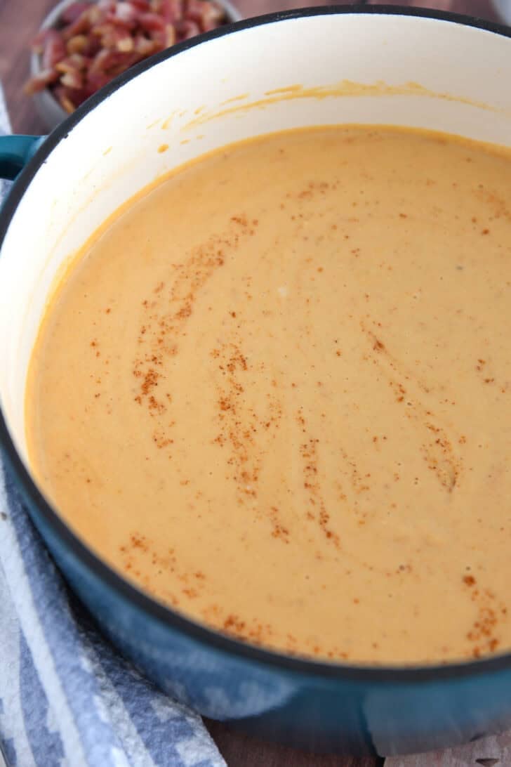 Blended butternut squash soup in soup pot with cayenne pepper.