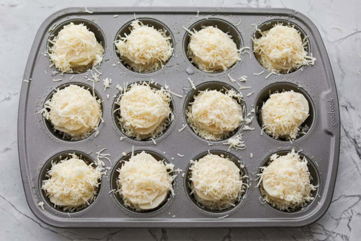 Potato stacks topped with cheese and ready to go in the oven. 