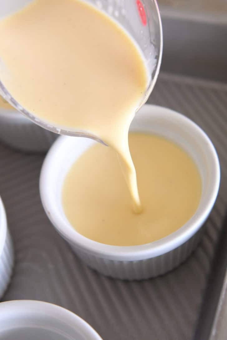 Pouring creme brulee mixture into 6-ounce ramekins in metal 9X13-inch pan.