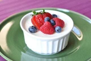 small white ramekin filled with cream and topped with fresh berries