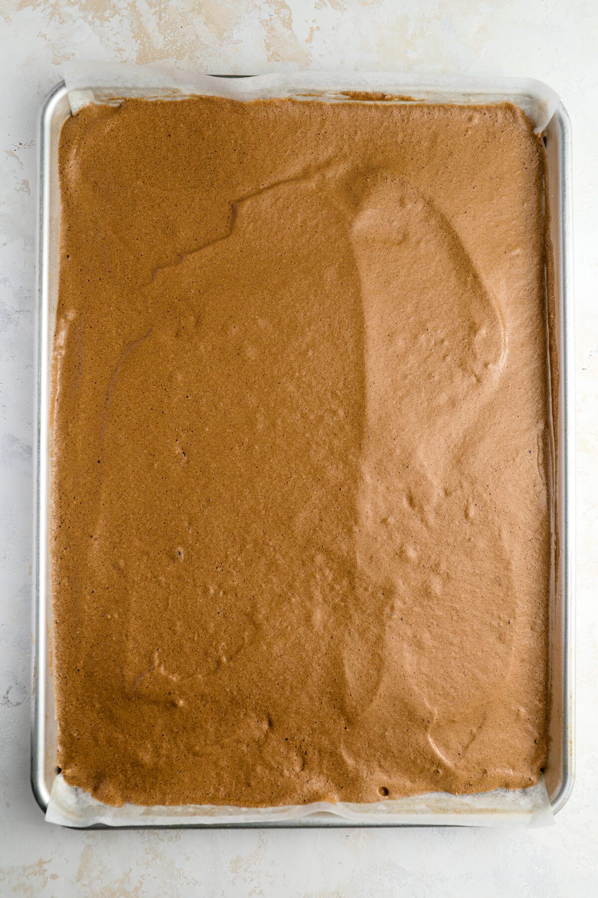 cake batter in parchment-lined jelly roll pan