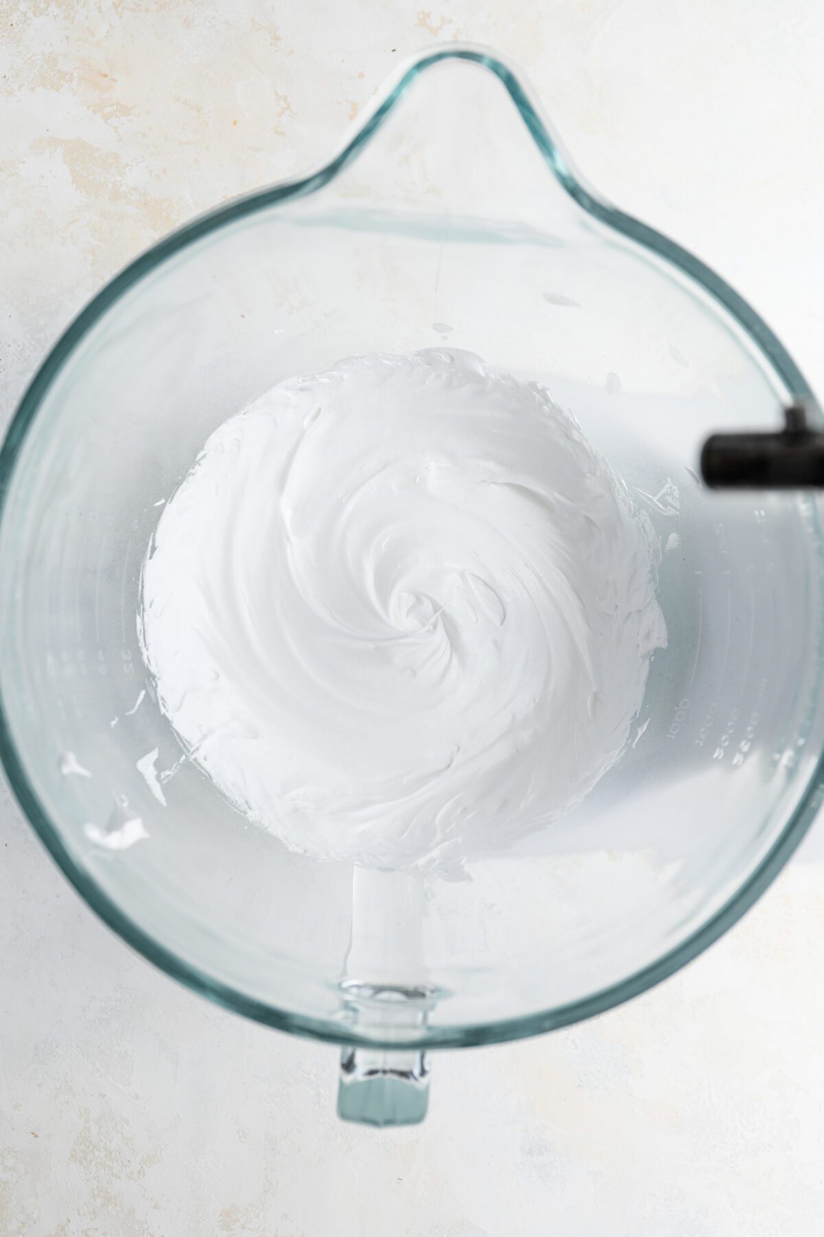 Mixing bowl with egg whites, cream of tartar, and sugar whipped to firm peaks