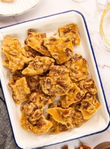 pecan praline pieces stacked on white rectangular serving platter