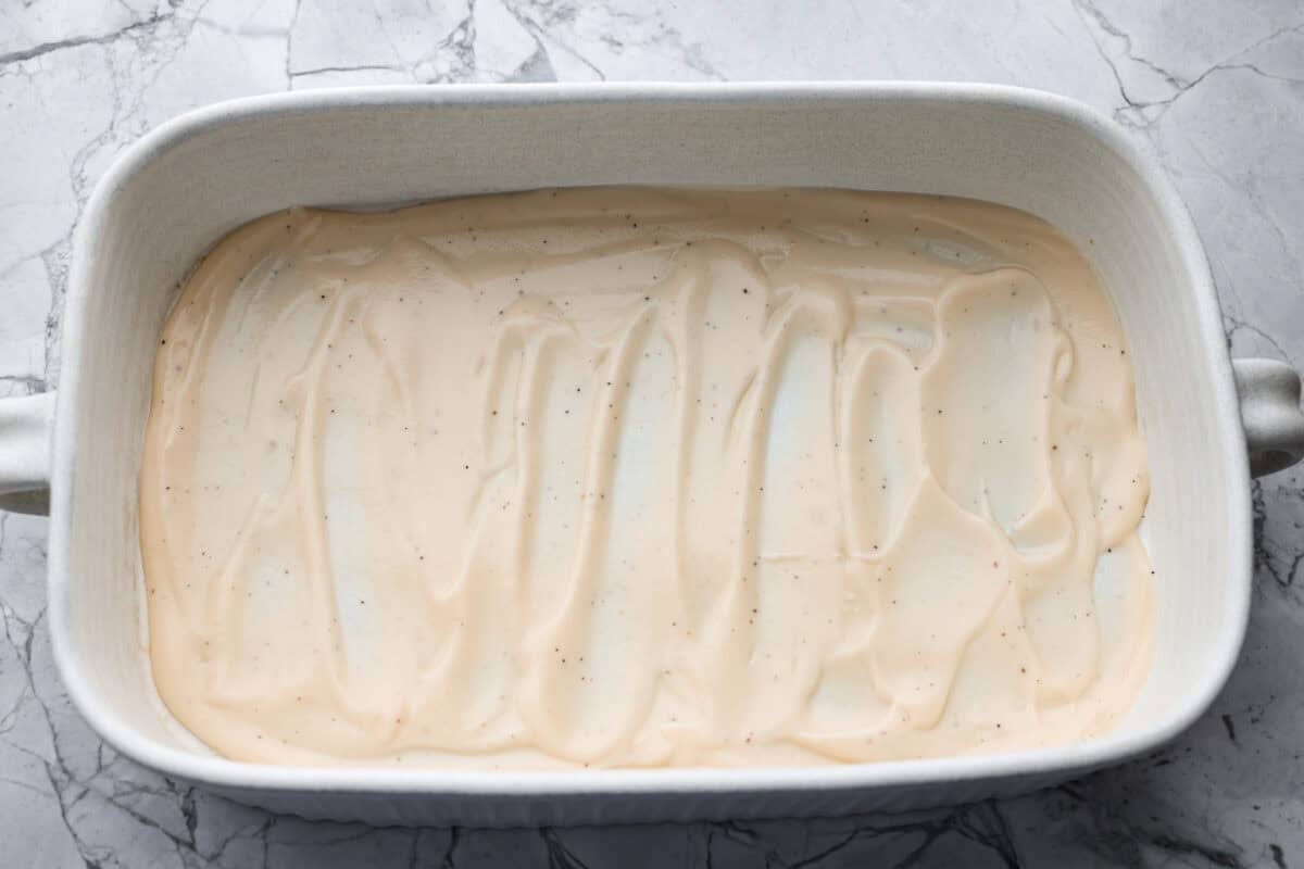 Alfredo sauce spread on the bottom of the baking dish. 