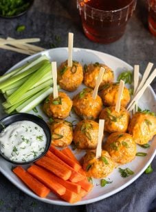 Buffalo chicken meatball on a plate with carrots, celery, and dip.