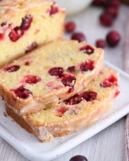 Two slices cut from cranberry orange loaf on white tray.