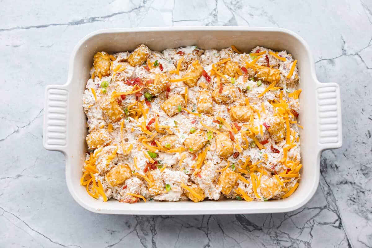 Tater tot and sauce mixture added to the bottom of the prepared baking dish.