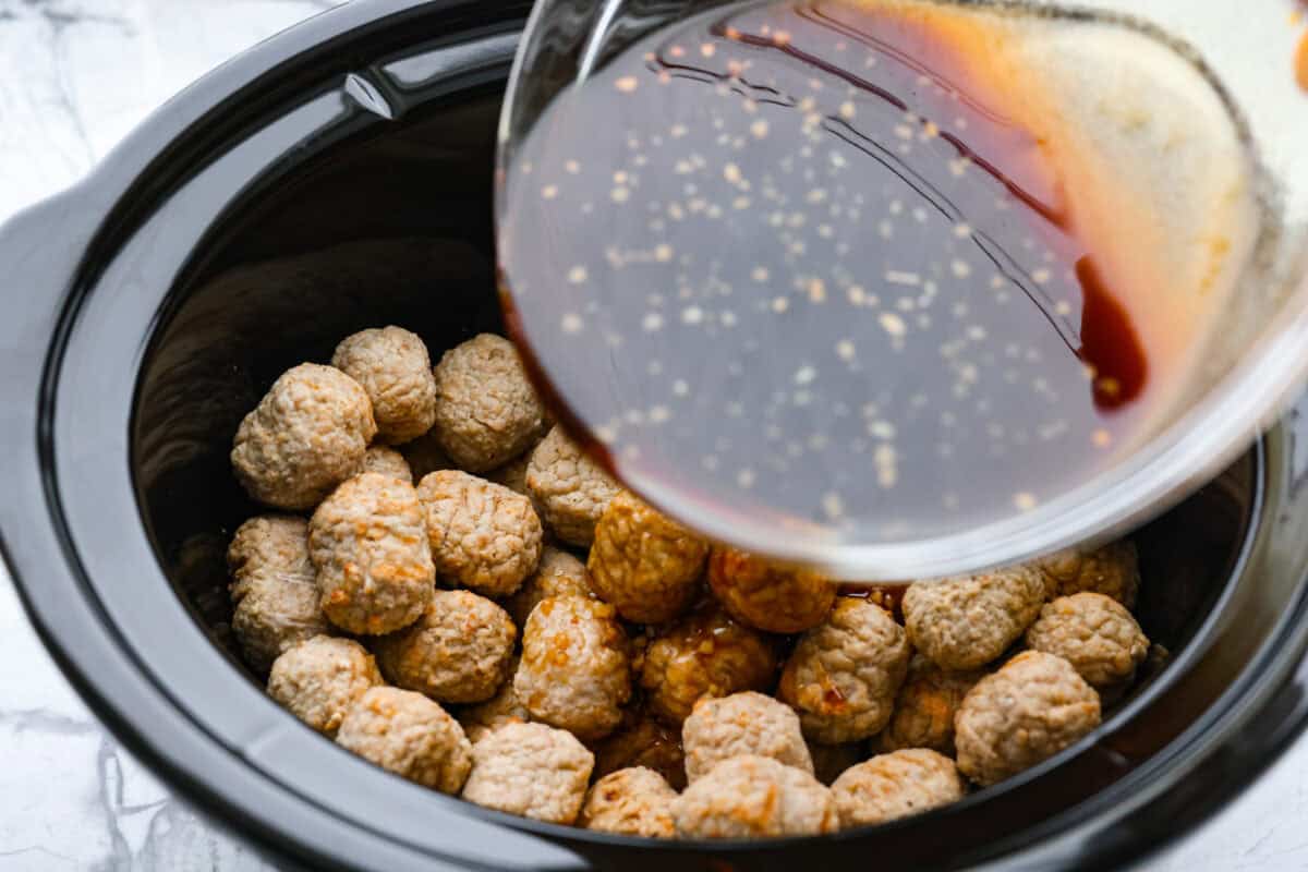 Someone pouring the sauce over the top of the meatballs. 