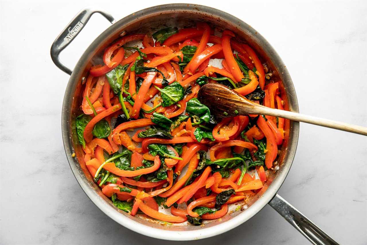 Peppers and spinach sautéed in a pan.