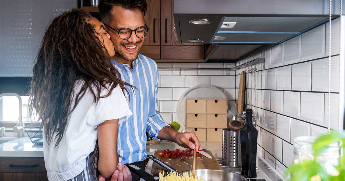 Married couple cooking together for anniversary celebration, showing teamwork and connection in their home kitchen