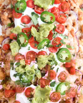 close up top down view of bbq chicken totchos with sour cream, tomatoes and guacamole