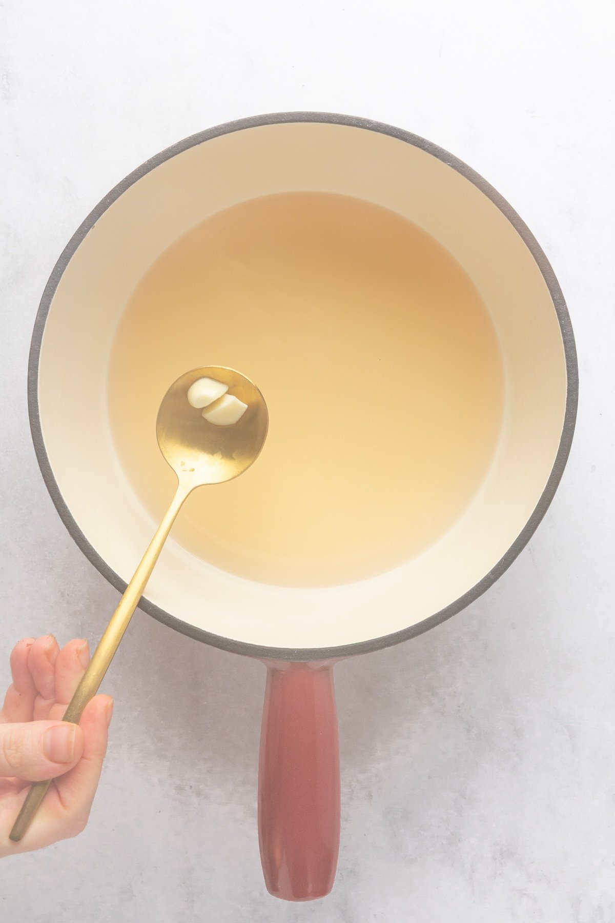 fondue pot with garlic removed from liquid