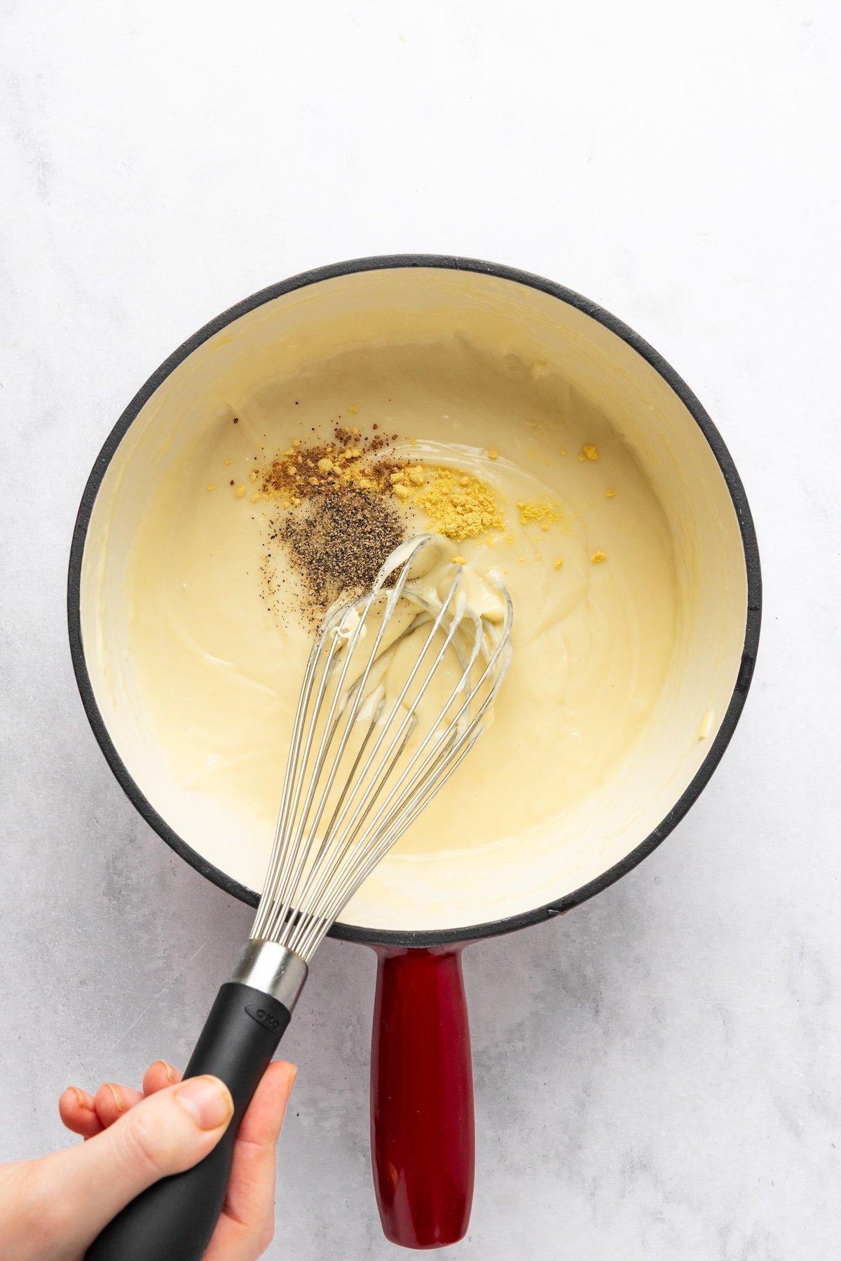 adding dry mustard, pepper, and nutmeg to melted cheese in fondue pot