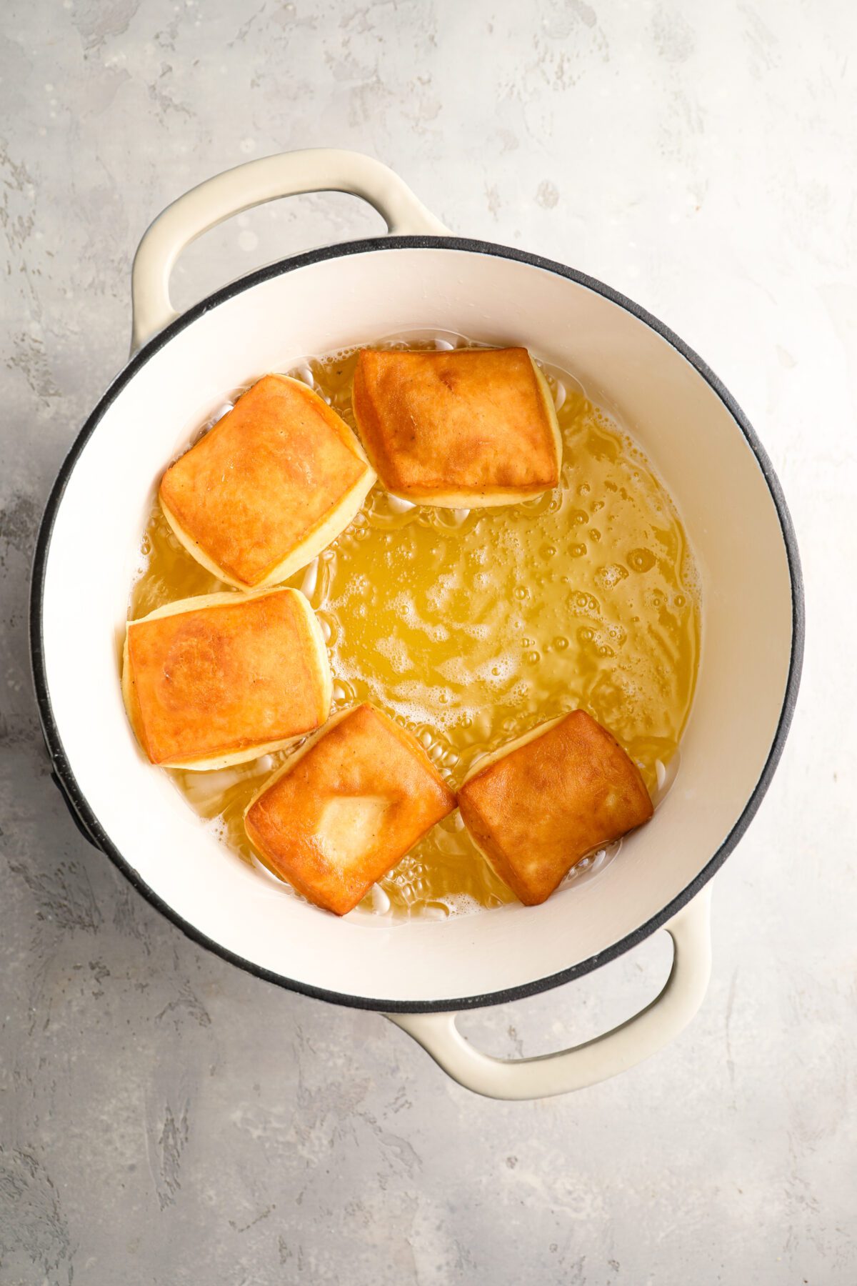 5 golden-brown beignets in large dutch oven with hot oil