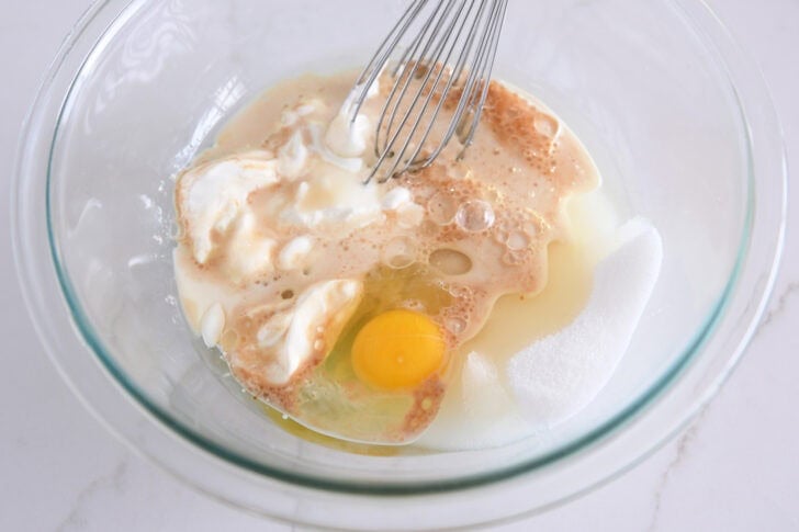 Glass bowl with sour cream, granulated sugar, egg and oil.